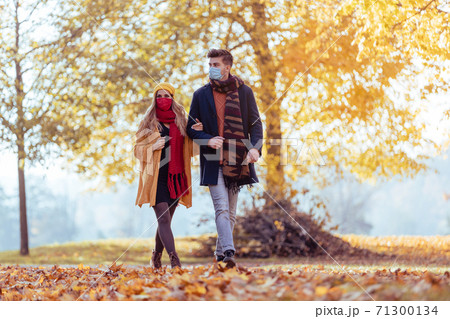 Couple wearing mask walking in autumn park 71300134