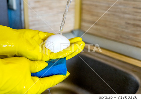 Washing fresh eggs in the kitchen sink with gloves and sponge. Washing fresh eggs in the kitchen sink with gloves and sponge. 71300326