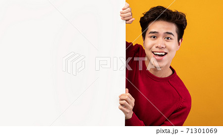 Asian guy hiding behind blank white advertising billboard Asian guy hiding behind blank white advertising billboard 71301069