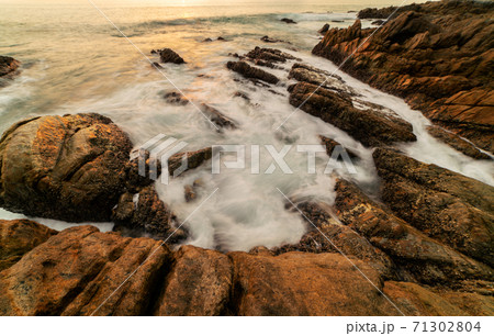 Long exposure image of Dramatic sky seascape with rocks in the foreground sunset or sunrise over sea scenery background. 71302804