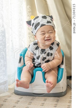 牛のコスプレをして窓辺でベビーチェアに座る赤ちゃん 牛のコスプレをして窓辺でベビーチェアに座る赤ちゃん 71304315