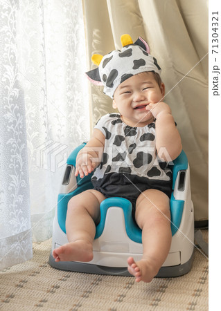 牛のコスプレをして窓辺でベビーチェアに座る赤ちゃん 71304321