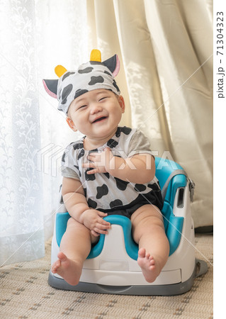 牛のコスプレをして窓辺でベビーチェアに座る赤ちゃん 牛のコスプレをして窓辺でベビーチェアに座る赤ちゃん 71304323