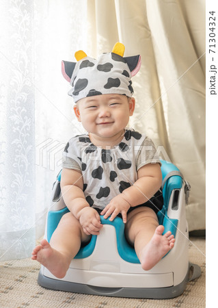 牛のコスプレをして窓辺でベビーチェアに座る赤ちゃん 牛のコスプレをして窓辺でベビーチェアに座る赤ちゃん 71304324