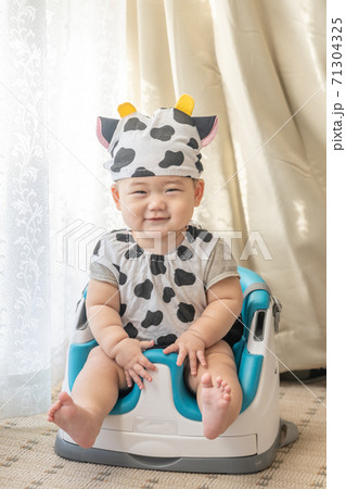 牛のコスプレをして窓辺でベビーチェアに座る赤ちゃん 牛のコスプレをして窓辺でベビーチェアに座る赤ちゃん 71304325