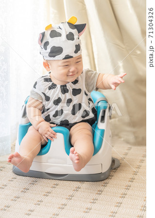 牛のコスプレをして窓辺でベビーチェアに座る赤ちゃん 牛のコスプレをして窓辺でベビーチェアに座る赤ちゃん 71304326