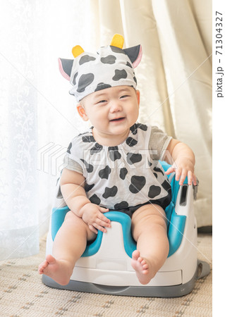 牛のコスプレをして窓辺でベビーチェアに座る赤ちゃん 71304327