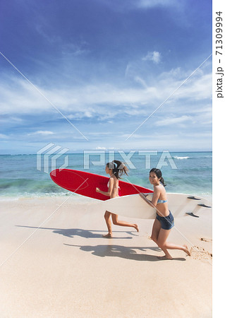 サーフボードを持って海辺を走る日本人日本人女性の写真素材