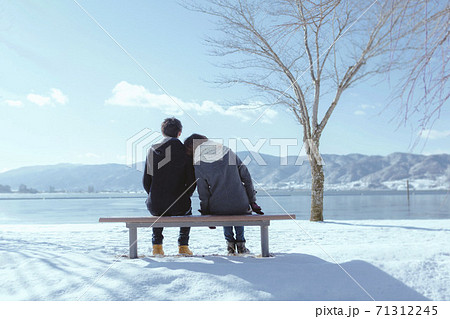 湖畔のベンチに座るカップルの後姿の写真素材