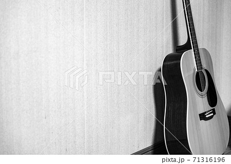 部屋の隅の壁に立てかけられたギターの写真素材