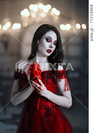 Bloodthirsty female vampire in red dress. Medieval interior 71318868