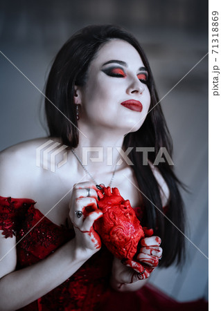 Bloodthirsty female vampire in red dress. Medieval interior Bloodthirsty female vampire in red dress. Medieval interior 71318869