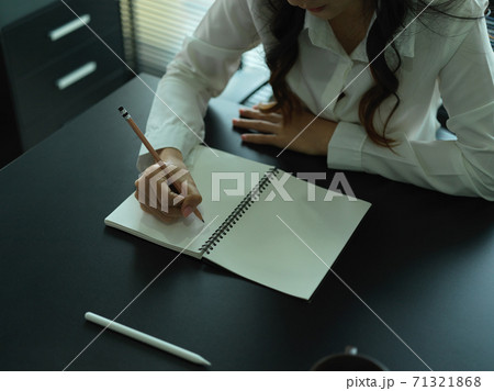 Female writing on notebook while working in office room Female writing on notebook while working in office room 71321868