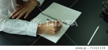 Female office worker writing on blank notebook on office table Female office worker writing on blank notebook on office table 71322139