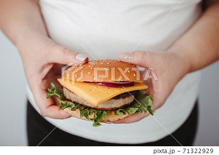 Overeating. Overweight woman with hamburger Overeating. Overweight woman with hamburger 71322929