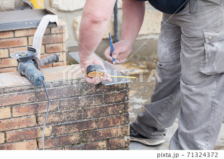 the tiler measures and puts marks to cut and lay a tile 71324372