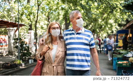 Portrait of happy senior couple walking outdoors in city or town, coronavirus concept. Portrait of happy senior couple walking outdoors in city or town, coronavirus concept. 71324772
