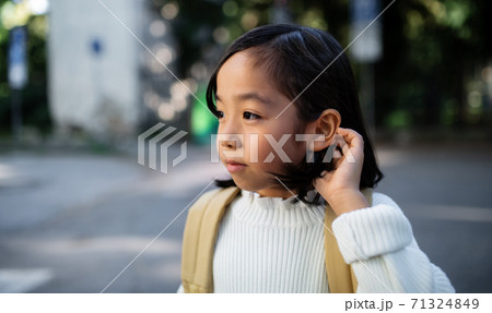 Portrait of small Japanese girl with backpack walking outdoors in town. 71324849