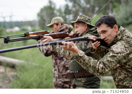 Hunters in Forest Aiming with Rifles Carefully. 71324850