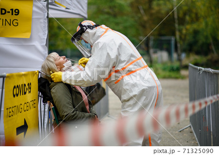 Senior woman in covid-19 testing center outdoors on street, coronavirus and swab taking concept. Senior woman in covid-19 testing center outdoors on street, coronavirus and swab taking concept. 71325090