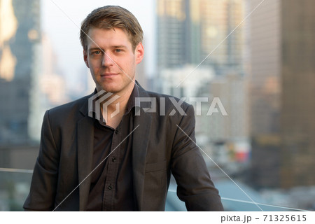 Face of young handsome businessman in suit against view of the city 71325615