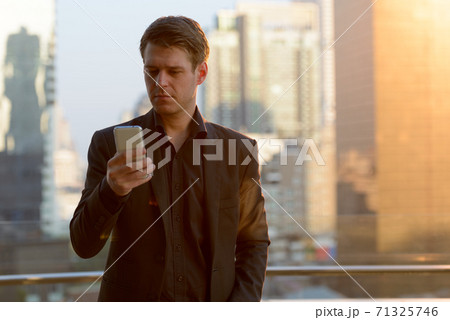 Young handsome businessman using phone against view of the city Young handsome businessman using phone against view of the city 71325746