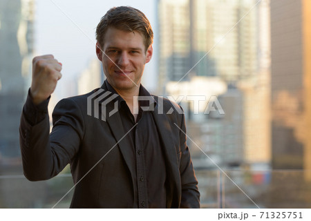 Young handsome businessman with fist raised against view of the city Young handsome businessman with fist raised against view of the city 71325751