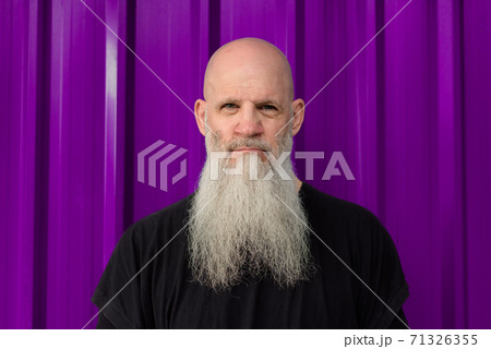 Mature handsome bald bearded man against metal sheet wall Mature handsome bald bearded man against metal sheet wall 71326355