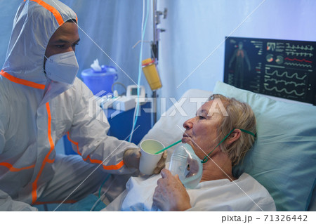 Doctor giving drink to covid-19 infected patient in bed in hospital, coronavirus concept. 71326442