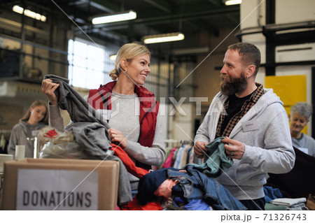 Volunteers sorting out donated clothes in community charity donation center. 71326743