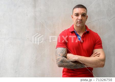 Handsome man with arms crossed against concrete wall 71326750