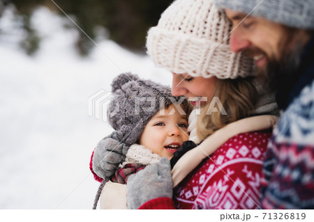 Father and mother with small child in winter nature, standing in the snow. Father and mother with small child in winter nature, standing in the snow. 71326819