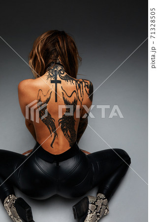 the back of a young girl with a tattoo . Tanned beautiful girl with a tattoo on the entire back 71328505