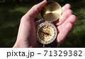 Person in forest using a compass to find direction 71329382