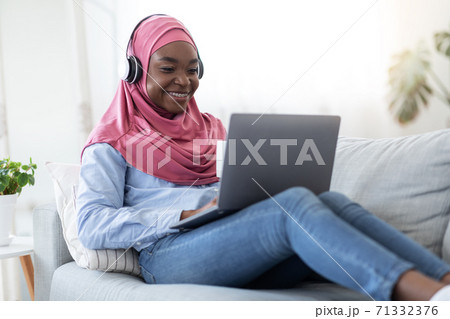 Home Pastime. Black Muslim Woman In Hijab Relaxing With Laptop And Coffee Home Pastime. Black Muslim Woman In Hijab Relaxing With Laptop And Coffee 71332376