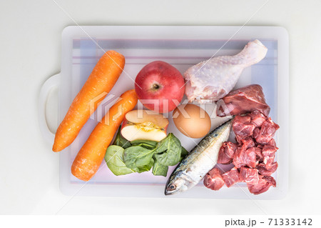 Overhead view of ingredients of barf raw food recipe for dogs consisting meat, organs, fish, eggs and vegetable on chopping board Overhead view of ingredients of barf raw food recipe for dogs consisting meat, organs, fish, eggs and vegetable on chopping board 71333142