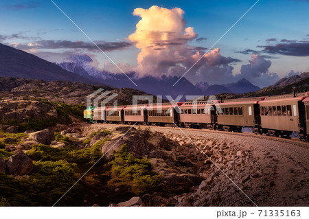 Old Historic Railroad Train is going over White Pass. Dramatic Colorful Sky Old Historic Railroad Train is going over White Pass. Dramatic Colorful Sky 71335163