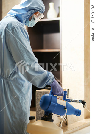 Worker in hazmat making disinfection in flat Worker in hazmat making disinfection in flat 71335252