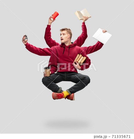Handsome multi-armed student levitating isolated on grey studio background with equipment Handsome multi-armed student levitating isolated on grey studio background with equipment 71335671