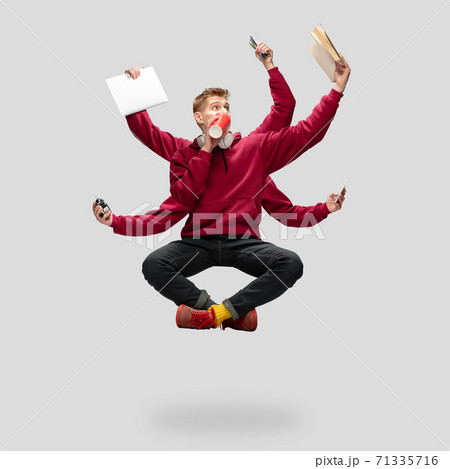 Handsome multi-armed student levitating isolated on grey studio background with equipment 71335716