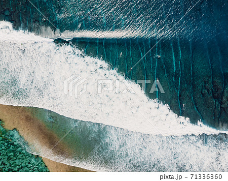 Aerial view of a surfers in blue ocean with waves. Top view 71336360