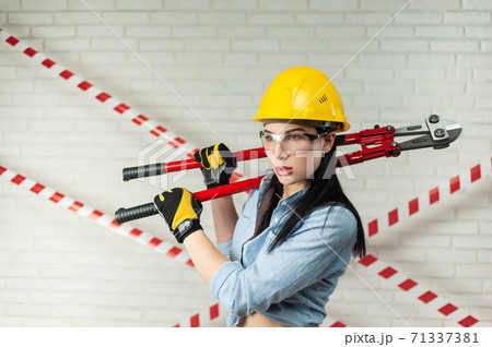 portrait of a female construction worker in a hard hat with a bolt cutter in her hands portrait of a female construction worker in a hard hat with a bolt cutter in her hands 71337381