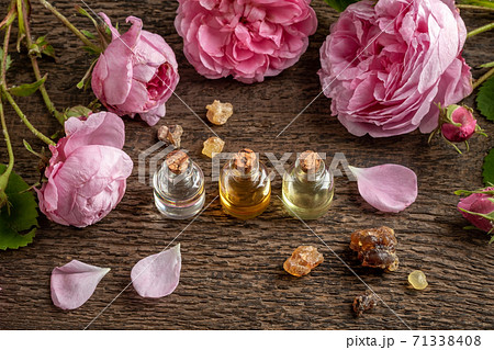 Essential oil bottles with frankincense resin and rose de mai flowers 71338408