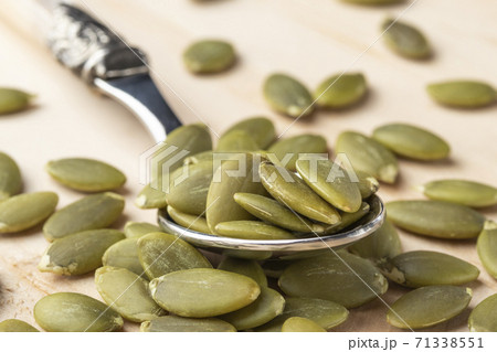 Pumpkin seeds in a dessertspoon on a wooden table close-up 71338551