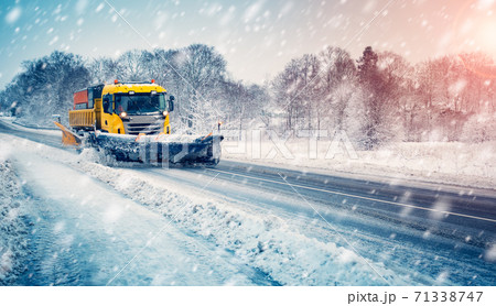 Snow plow truck cleaning snowy road in snowstorm 71338747