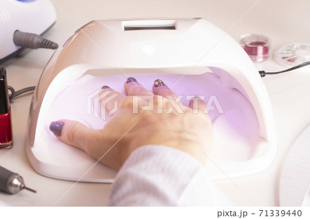A girl's hand in an ultraviolet nail lamp with nail polish files 71339440