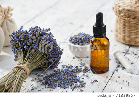 Dropper bottle of lavender essential oil, sachet bags and bouquet of dried lavender flowers on white wooden table. 71339857