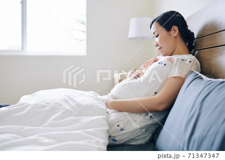 Pregnant woman sitting in bed 71347347