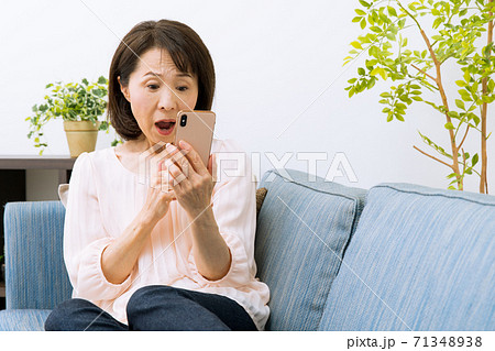 スマートフォンを見る女性　驚く　困る 71348938