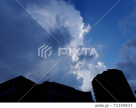 マンションのシルエット越しの空と雲1横の写真素材